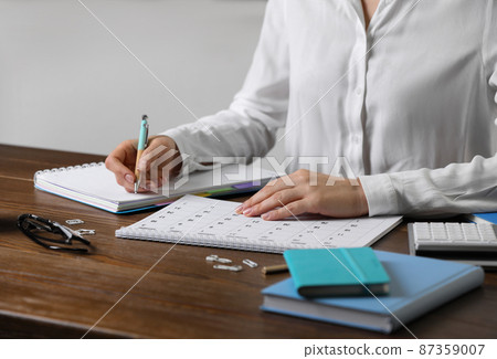Woman making schedule using calendar at wooden table, closeup 87359007