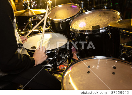 Young girl training to play on the drum kit by wooden mallets at school, education concept 87359943
