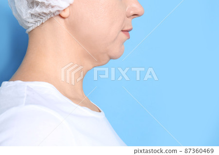 Mature woman with double chin on blue background, closeup. Space for text 87360469