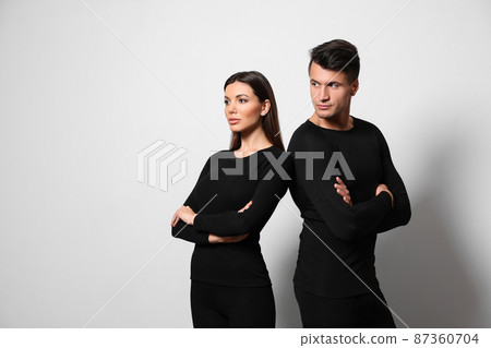 Couple wearing thermal underwear on light grey background. Space for text 87360704