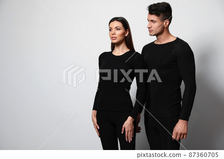 Couple wearing thermal underwear on light grey background. Space for text 87360705