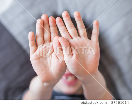 Little boy covers his face with hands. Child refuses to be photographed. Playful kid shows his palm hands instead of laughing face. Little boy covers his face with hands. Child refuses to be photographed. Playful kid shows his palm hands instead of laughing face. 87361014