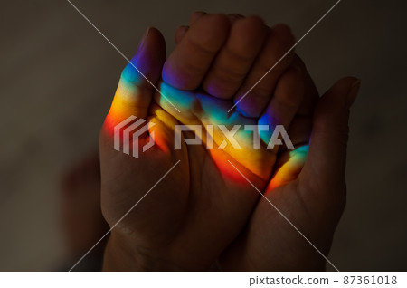 Rainbow ray on a woman's hand. Rainbow ray on a woman's hand. 87361018