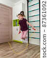 A little girl goes in for sports in her room. 87361092