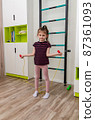 A little girl goes in for sports in her room. 87361093