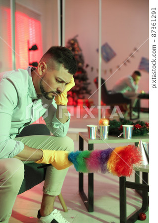 Man with dusting brush suffering from hangover in messy room after New Year party Man with dusting brush suffering from hangover in messy room after New Year party 87361291