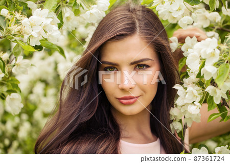 Romantic woman with perfect windy brown hair in spring flowers garden 87361724