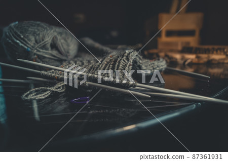 Knitting wool sock. A ball of natural yarn made of wool. His hobby is hand knitting. Selective focus, black background 87361931