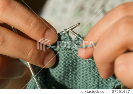 Close-up hand knitting. Hobbies, handicrafts. Knitting warm clothes from woolen fine yarn by hand on metal needles. Selective focus 87361937