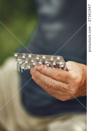 Portrait of helderly man holding pills 87361947