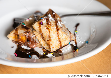 Stuffed sweet crepes with chocolate syrup 87362031