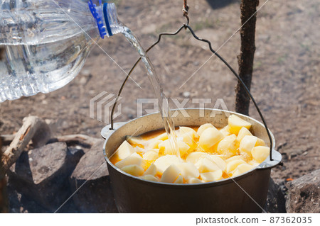 Adding water out of plastic bottle in a cauldron Adding water out of plastic bottle in a cauldron 87362035