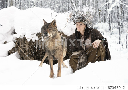 Female forest dweller with a big gray wolf in the winter forest 87362042