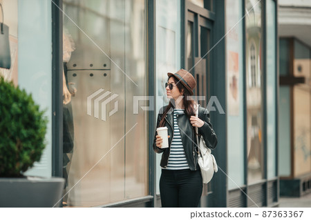 Happy young woman in hat on the street of european city. Happy young woman in hat on the street of european city. 87363367