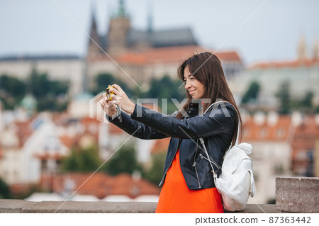 Young woman taking selfie on smartphone on Charles Bridge in Prague, 87363442