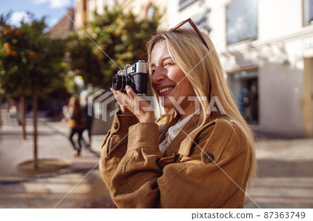 Side photo of young lady taking photo with retro camera outside 87363749