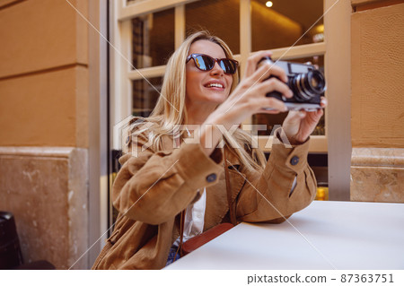 Smiling woman tourist sitting at the table outside Smiling woman tourist sitting at the table outside 87363751