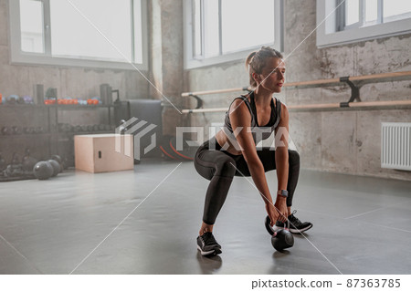 Athletic woman working with dumbbell in gym 87363785