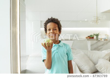 Healthy eating, childhood, nutrition concept. Small boy eating green apple indoor 87363789