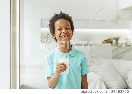 Laughing kid boy drinking milk at home 87363790