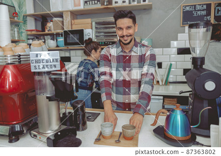 Portrait of happy man barista serving visitors 87363802