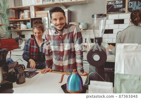 Positive photo of male barista standing behind counter Positive photo of male barista standing behind counter 87363848