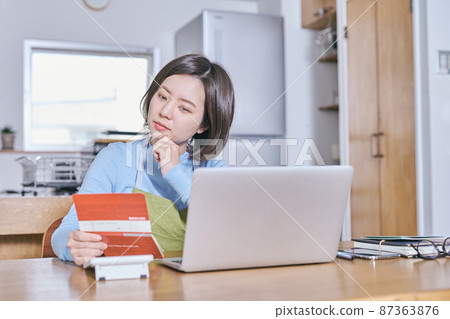 一個穿著圍裙的年輕女人看著她的存摺，想著她的晚年 87363876