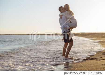 Full length of carefree couple having fun standing on seashore at sunset Full length of carefree couple having fun standing on seashore at sunset 87363897