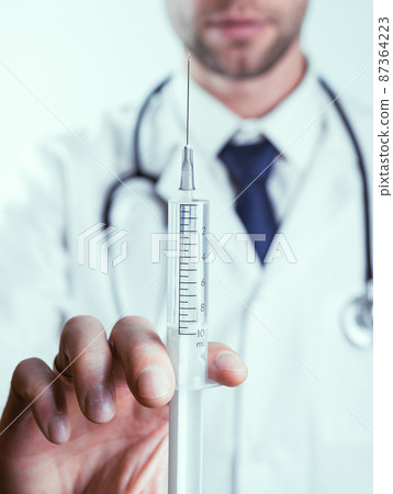 Syringe needle medical injection. Selective focus, doctor hand in blue gloves holding syringe with needle. Hospital white doctor gown, stethoscope. Syringe with flu vaccine with copy space. Syringe needle medical injection. Selective focus, doctor hand in blue gloves holding syringe with needle. Hospital white doctor gown, stethoscope. Syringe with flu vaccine with copy space. 87364223