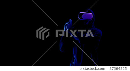 Virtual reality game vr. Young man in digital glasses for virtual reality technology isolated on dark neon background. Study and virtual world in 3D simulation. Virtual reality game vr. Young man in digital glasses for virtual reality technology isolated on dark neon background. Study and virtual world in 3D simulation. 87364225