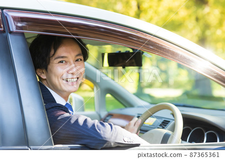 A man driving a car in a suit 87365361