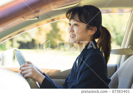 Woman driving a car in a suit Woman driving a car in a suit 87365401