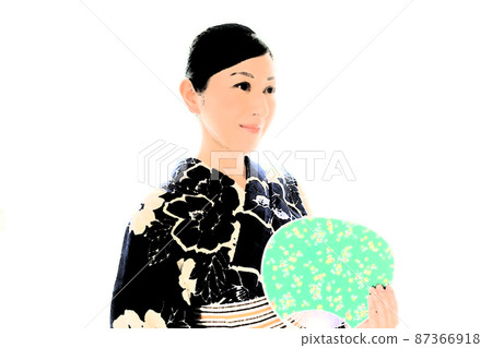 A woman wearing an indigo-dyed yukata and holding a uchiwa A woman wearing an indigo-dyed yukata and holding a uchiwa 87366918