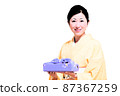 A smiling middle woman wearing a kimono and holding a furoshiki wrap 87367259