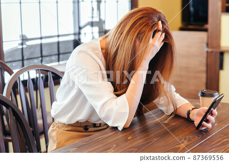 A woman holding her head in front of a computer to worry 87369556