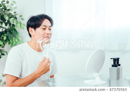 A man using a facial roller (smile) A man using a facial roller (smile) 87370563