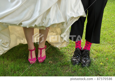 Close up of a Bride and Groom's Funky pink wedding heels and groom's socks 87370586