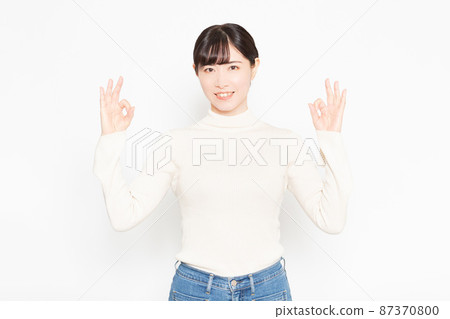 Woman standing in front of white background and making an OK gesture Woman standing in front of white background and making an OK gesture 87370800