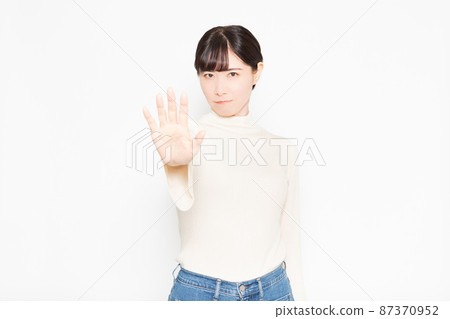 Woman standing in front of white background and making NG gestures Woman standing in front of white background and making NG gestures 87370952