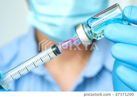 doctor's hand holds a syringe and a blue vaccine bottle at the hospital. Health and medical concepts. doctor's hand holds a syringe and a blue vaccine bottle at the hospital. Health and medical concepts. 87371200