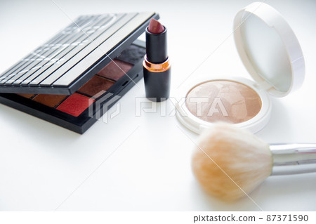 The white face powder and bronzer, black packaging with eye shadow, lipstick and brush lying on white background. High quality photo 87371590