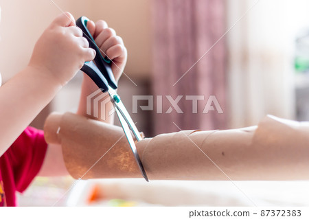 Little kig hold big scissors and cut paper at home it is dangerous 87372383