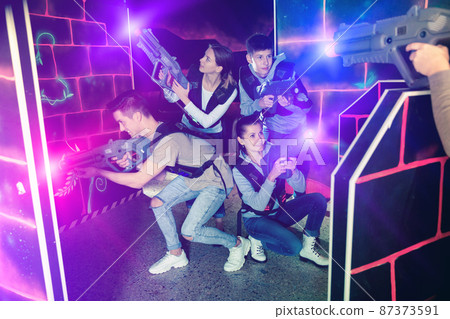Modern young people with laser pistols playing laser tag on dark Modern young people with laser pistols playing laser tag on dark 87373591