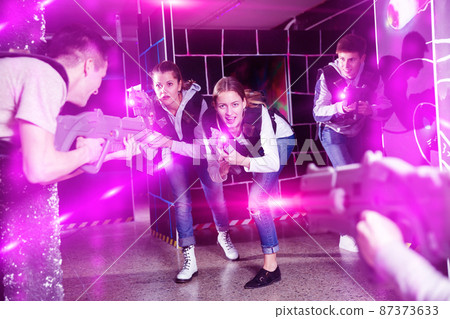 Girl with friends playing laser tag Girl with friends playing laser tag 87373633