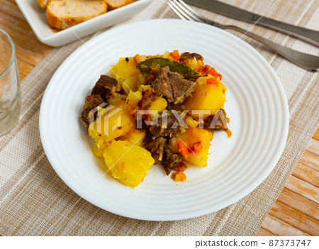 Portion of braised potatoes with beef 87373747