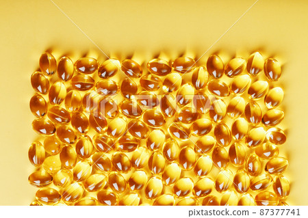 Capsules in a shell with liquid vitamin D3 on a yellow background and a place for text Capsules in a shell with liquid vitamin D3 on a yellow background and a place for text 87377741