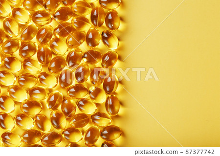 Capsules in a shell with liquid vitamin D3 on a yellow background and a place for text Capsules in a shell with liquid vitamin D3 on a yellow background and a place for text 87377742
