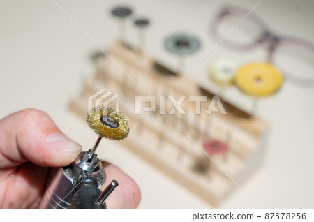 An optician technician polishes the frame of glasses. A professional optician fixes glasses. An optician technician polishes the frame of glasses. A professional optician fixes glasses. 87378256