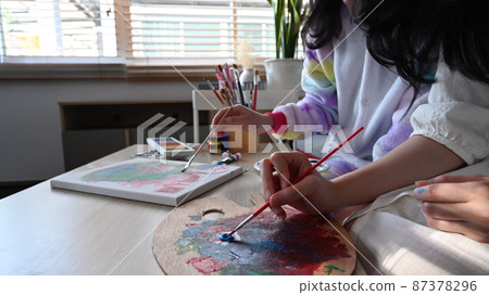 Two girl enjoy painting pictures with watercolor while spending weekend at home together. Two girl enjoy painting pictures with watercolor while spending weekend at home together. 87378296