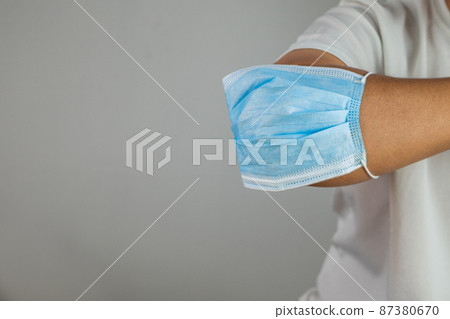 Medical concept. Touching with elbow for disease protection. Such as influenza, flu, Covid-19, dust pm2.5. This close up shot is focused on mask. Copy space. 87380670